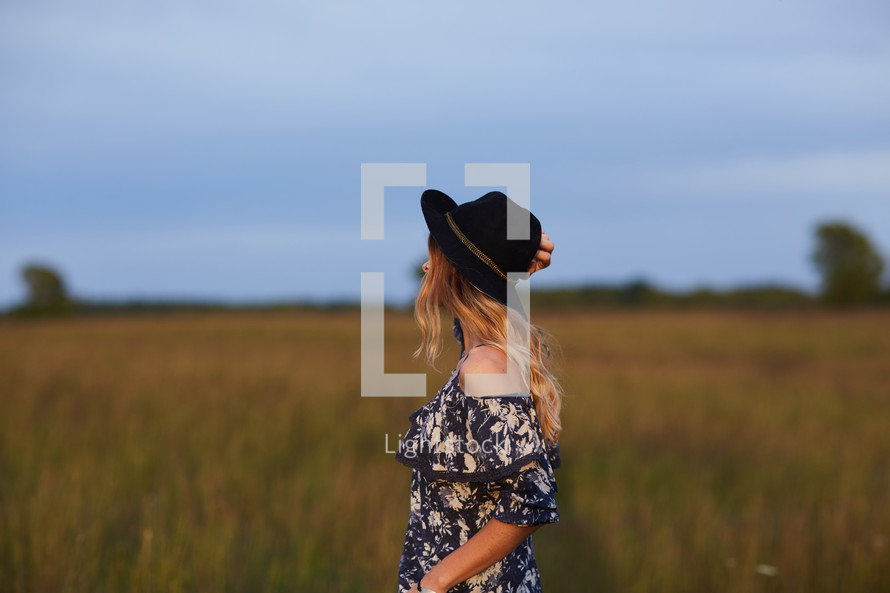 a woman in a dress walking through a field 