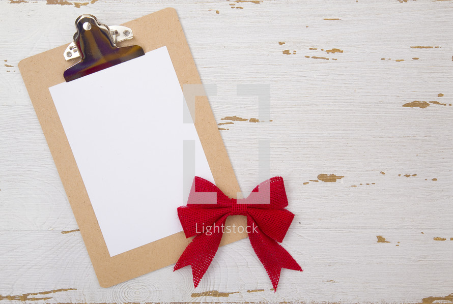 red bow and white paper on a clipboard 