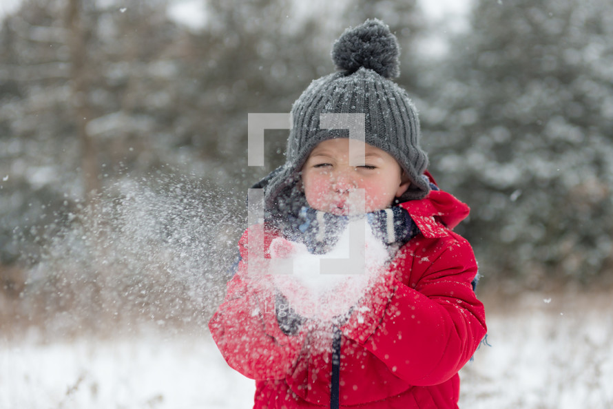 a boy child blowing snow 