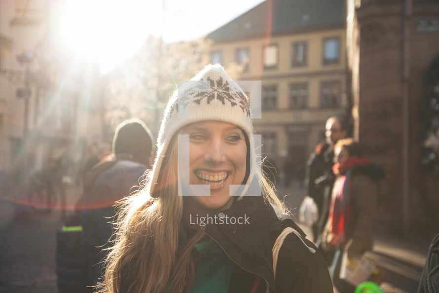 face of a smiling woman standing in a courtyard 