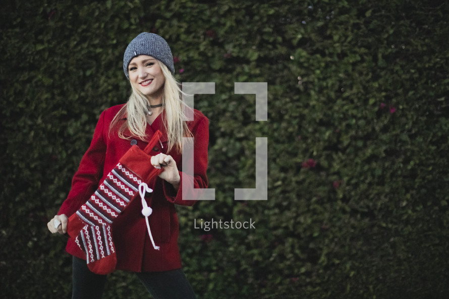 a woman holding a Christmas stocking outdoors 