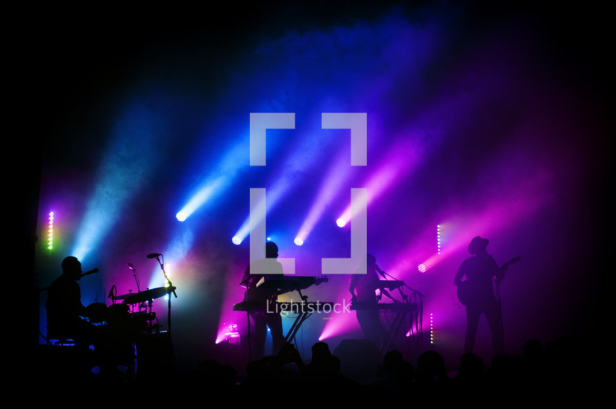 blue and purple stage lights on a band on stage at a concert 