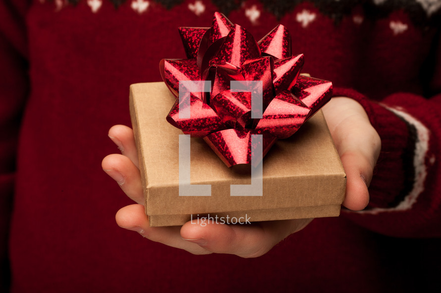 a man in a sweater holding a gift box 