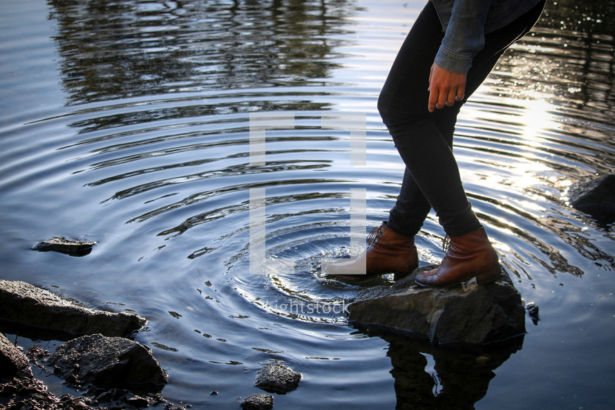 a woman tipping her toe in boots in water 