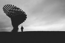 silhouette of a man standing next to a sculpture 