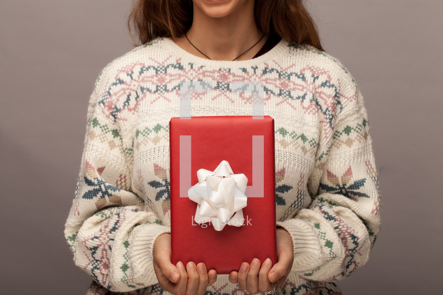 a woman in a Christmas sweater holding a wrapped git