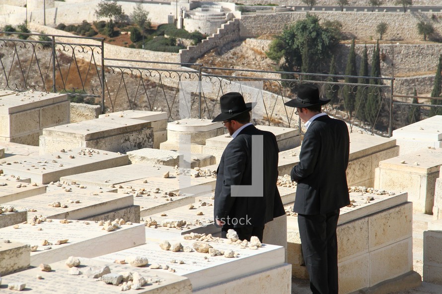 Jewish men leave stones at the grave of a loved one on the Mount of Olives 