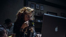 woman drinking coffee at a laptop 
