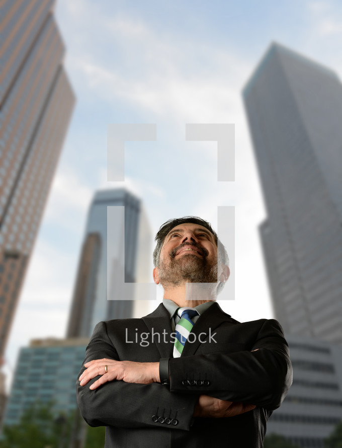 businessman in a city looking up 