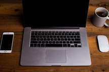 open laptop on a desk, iPhone, coffee mug