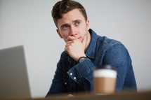 a man thinking sitting behind a computer 