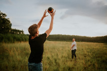 father and son throwing and catching a football in a field 