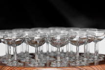 Many elegant empty glasses of wine or champagne on the wooden table in wedding day. Set of blank empty glasses displayed in rows. Preparation for the holiday.