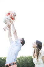 father holding his baby daughter in the air 