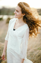 a woman with curly hair blowing in the breeze 