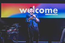 welcome sign and worship leader on stage 