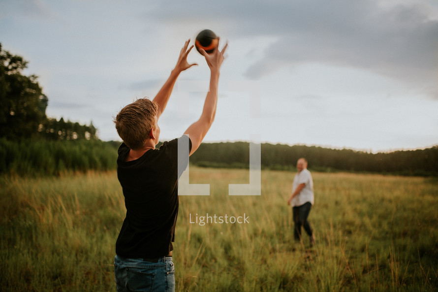 father and son throwing and catching a football in a field 