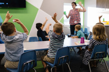 kids with hands raised in a classroom 