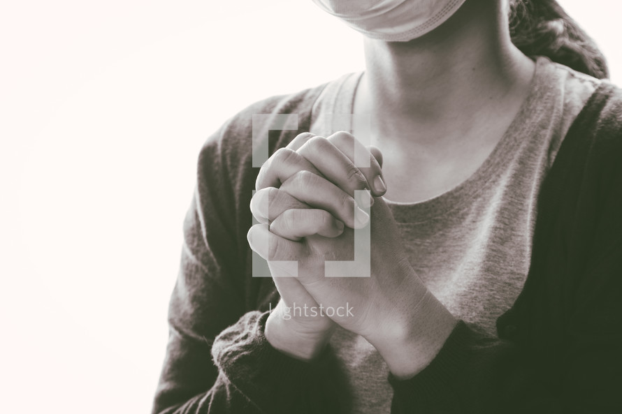 a woman praying wearing a mask 