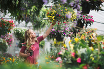 a young woman picking out flowers at a garden center 