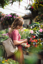 a young woman picking out flowers in a garden center greenhouse 