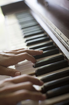 hands playing piano keys 