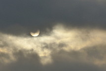 sun partially obscured by gray clouds in early morning