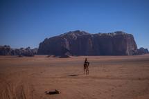 man riding a camel through desert landscape in Jerusalem 