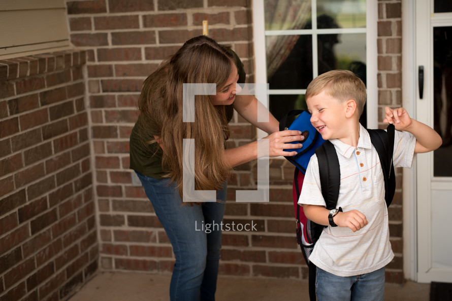 a mother helping her son get ready for school 
