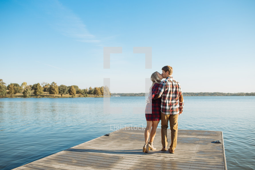 a couple kissing at the end of a dock 