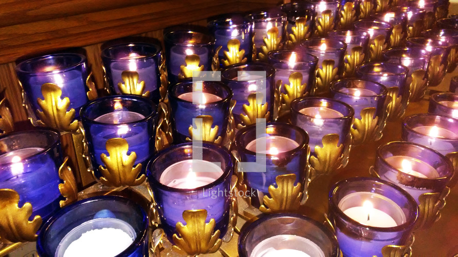 Four Rows of Candles burning during a prayer vigil at church during a candle light service where the congregation is invited to worship and pray and meditate on the presence of God. 