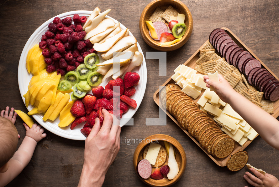 people eating fruit and a meat and cheese platter 