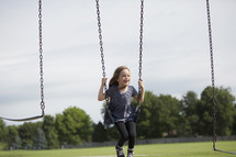 A little girl swinging on the playground.