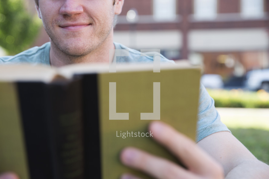 man reading a book outdoors 