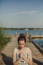 girl praying by a lake 