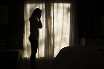 silhouette of a crying woman in her room.