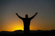 teen boy standing in warm sunlight with outstretched arms 