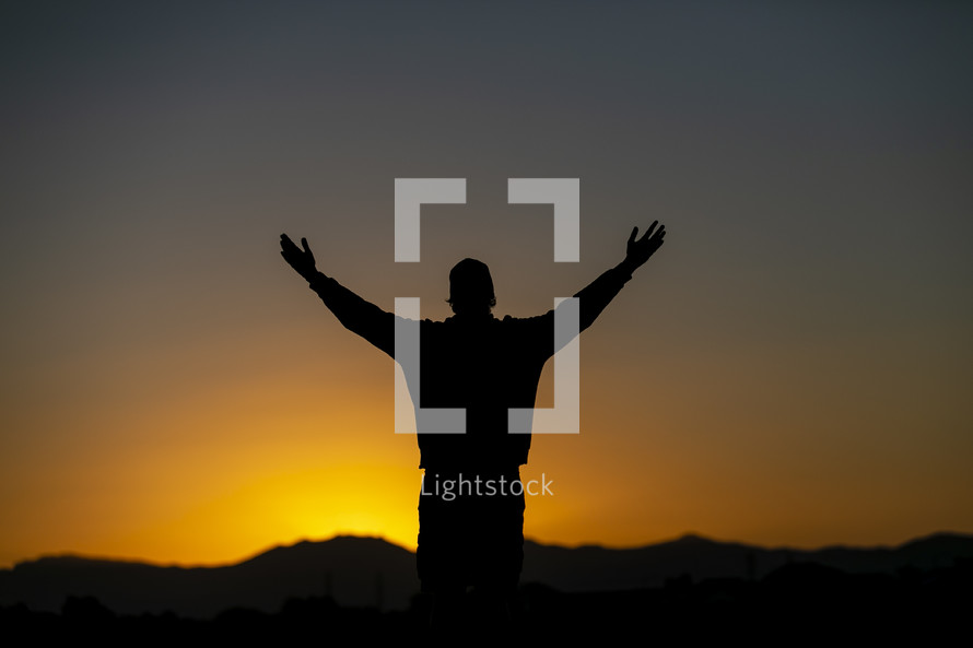 teen boy standing in warm sunlight with outstretched arms 