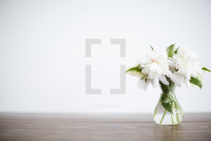 vase of white flowers on a wood table 