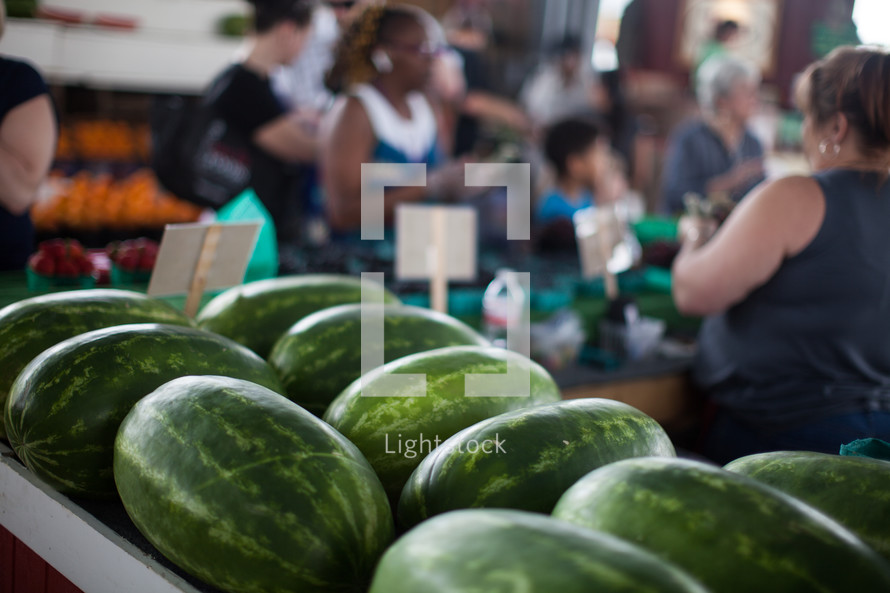watermelon and people shopping at a farmers market 