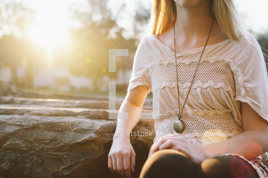 torso of a woman sitting outdoors under sunlight 