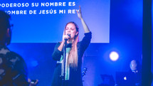 woman on stage singing at a worship service