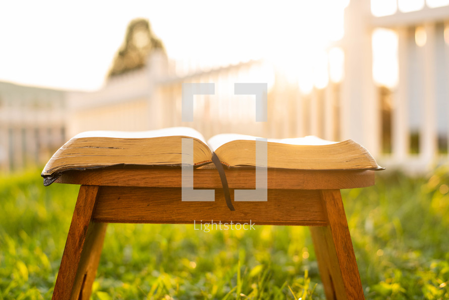 open Bible in a wood chair outdoors 