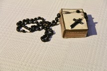 Prayer rosary and Christian cross on an old Bible 