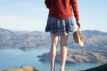 woman standing on a mountaintop looking down at the water below 