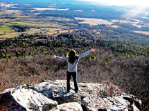 woman standing at the top of a mountain with her arms spread