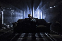 man sitting on a couch in a dark room alone