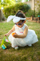 toddler girl with an Easter basket and bunny ears wearing an Easter dress 