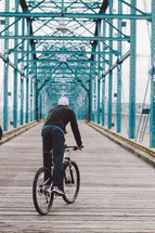 a man on a bicycle on a bridge 