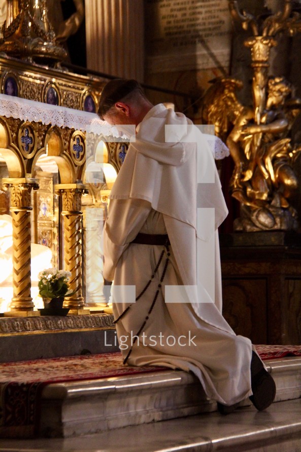 a monk praying in front of a tomb of a saint 